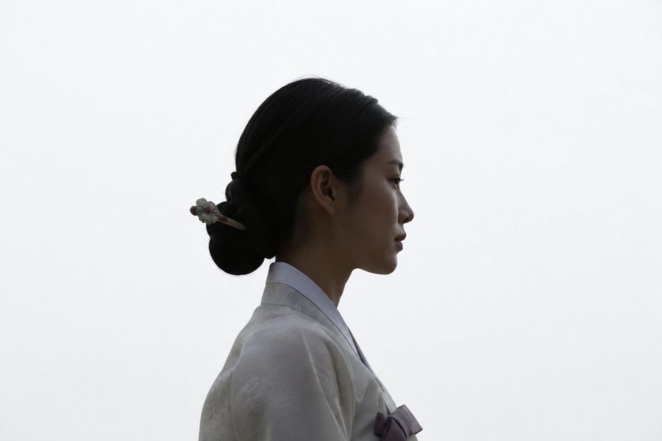 Profile silhouette of a woman in hanbok against a white sky